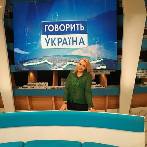 Анна Долід біля екрана з логотипом «Говорить Україна»